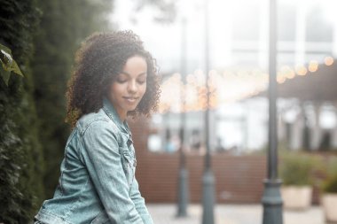 Siyah, genç ve güzel bir kız dışarıda dinleniyor. Sokak hipster portresi. Yürüyen öğrenci kadın.