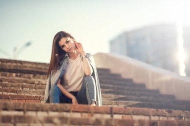 Moda kadını portresi. Genç, güzel, modaya uygun bir kız. Güneşli yaz şehri sokağı.