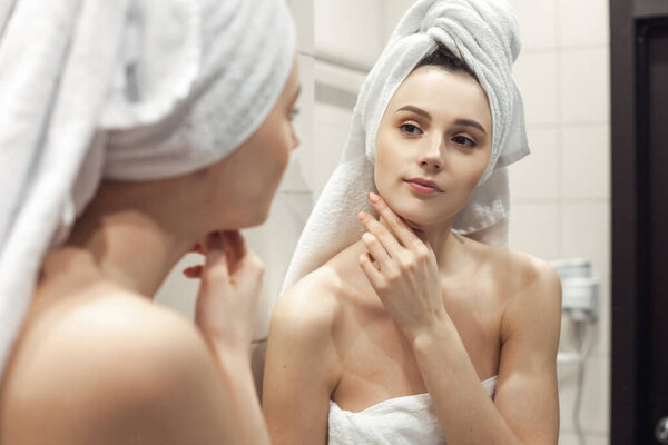 Young woman in bathroom behind mirror. Skincare  treatment concept