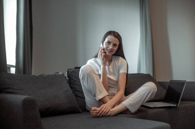 Modern dizüstü bilgisayarı olan genç bir kadın evdeki kanepede oturuyor. Boş zamanlarında internette gezinen mutlu kız... 