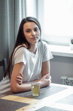 Güzel genç bayan sıcak içecek içiyor. Çekici kız evde dinleniyor.