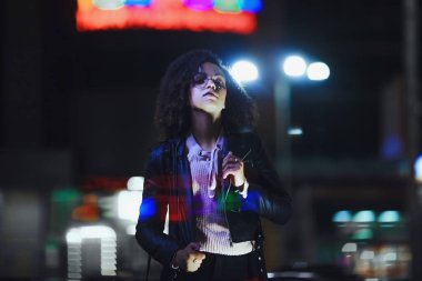 Genç, kıvırcık, Afro-Amerikan kızın portresi. Gece şehir ışıkları. Neon aydınlatması