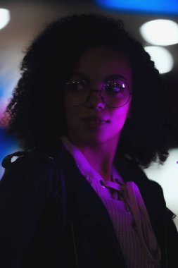 Genç, kıvırcık, Afro-Amerikan kızın portresi. Gece şehir ışıkları. Neon aydınlatması