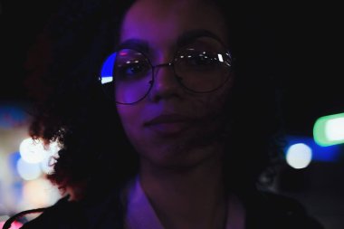 Genç, kıvırcık, Afro-Amerikan kızın portresi. Gece şehir ışıkları. Neon aydınlatması