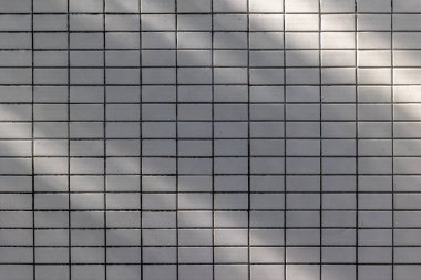 Beyaz fayanslı duvar yüzeyindeki ışık ve gölge ızgara desenli.