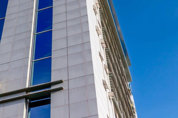 Açık mavi gökyüzüne karşı camdan pencereleri olan modern gökdelenler..