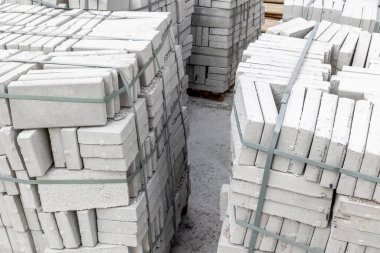 İnşaat alanında kayışlarla bağlanmış beton tuğla yığınları.