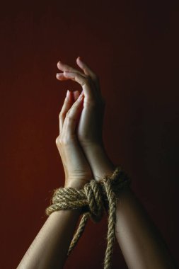 Koyu arkaplanda ip ile bağlanmış kadın elleri.