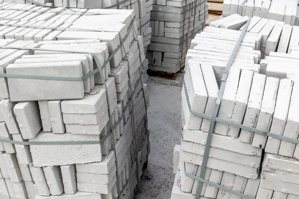 İnşaat alanında kayışlarla bağlanmış beton tuğla yığınları.