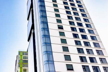 Mavi gökyüzüne karşı cam cepheli modern yüksek katlı ofis binası.