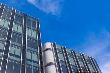 Mimari detaylarla dolu açık mavi gökyüzüne karşı modern cam bina.