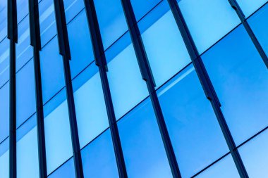 Mavi cam paneller ve metal kirişlerle modern mimari detay.