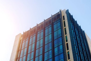 Açık mavi gökyüzü altında modern cam ofis binası.