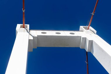 Açık mavi gökyüzüne karşı beyaz süspansiyon köprüsünün yukarı doğru görünümünü özetle.