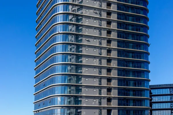 Açık mavi gökyüzü altında cam cepheli modern gökdelenler..