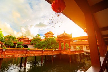 Gün batımında huzurlu Asya tapınağı. Fenerler ve sakin su yansıması..