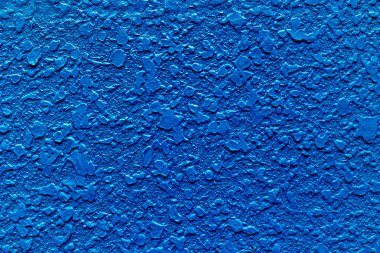 Textured blue stucco wall with rough surface and vivid color.