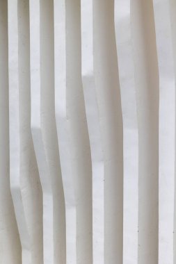 White textured minimalist wall with vertical lines and shadows.