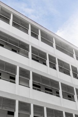 Modern white building with louvered windows against a clear blue sky.
