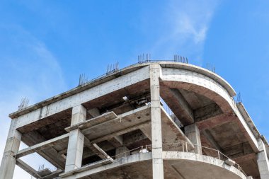 Incomplete concrete building structure under clear blue sky.