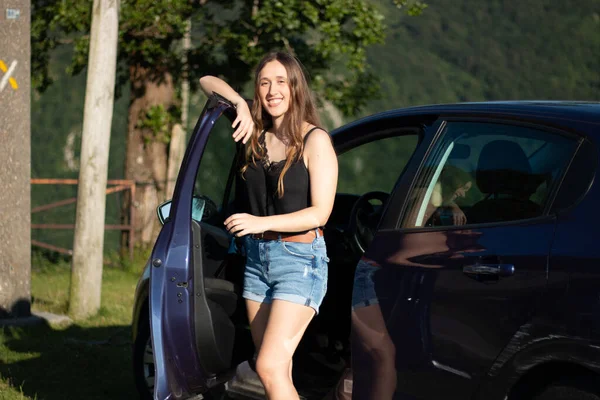 Genç kız güneşli bir günde yeni arabasına biniyor.