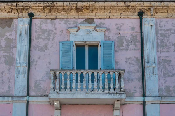 Closeup view of old pink building with white window and door