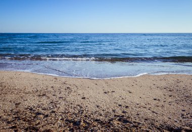 Dalgalar çöl plajın kumları üzerinde