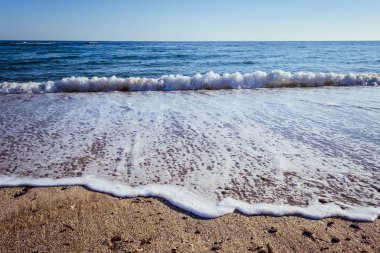Dalgalar çöl plajın kumları üzerinde