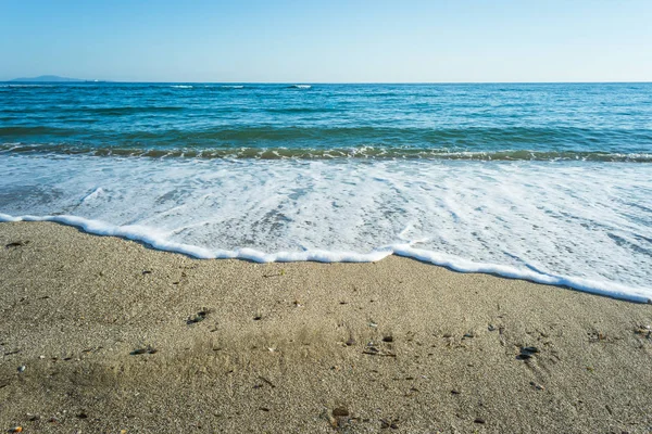 Dalgalar çöl plajın kumları üzerinde