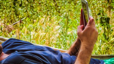 yaz güneşli bir gün hamakta bir tablet kullanarak adam closeup