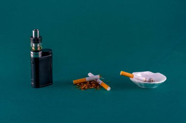 closeup of lit cigarette, broken cigarette and e-cigarette vaporizer on colored background clipart