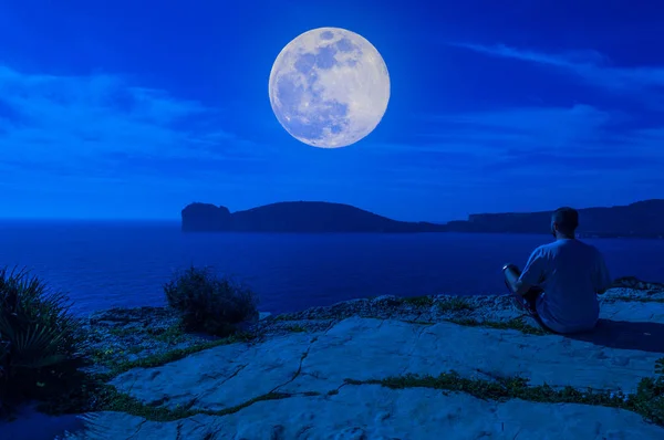 Hombre en la costa mirando la luna — Foto de Stock