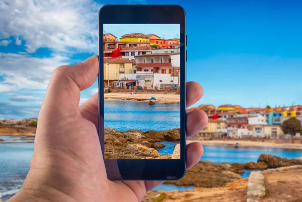 Fotografía de la mano con un smartphone en la playa dentro del pueblo de Porto Torres, Cerdeña — Foto de Stock