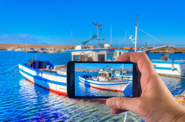 Toma de foto a mano con un smartphone de un barco pesquero en el puerto en verano — Foto de Stock