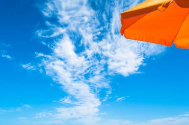 Yaz bulutlu bir günde deniz tarafından Turuncu plaj şemsiyesi