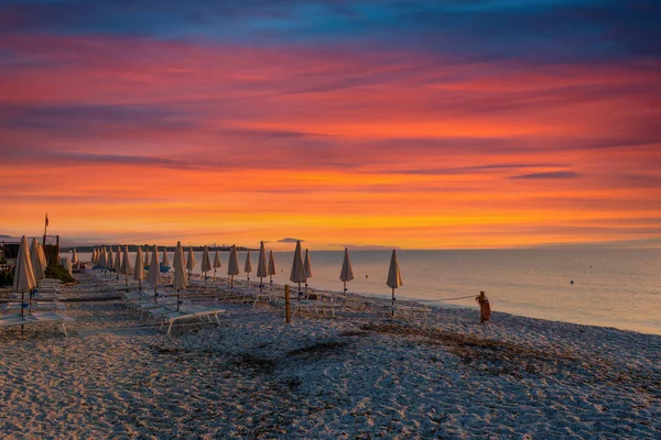 Sahilde sıra sıra kapalı şemsiyeler dramatik renkli gündoğumunda
