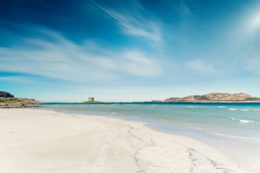 Güneşli bir günde, beyaz kumları ve berrak suyuyla boş bir La Pelosa plajı manzarası.
