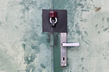 Alüminyum sapı ve asma kilidi olan kapı. Dokunulmuş yeşil levha metal kapı detayı.