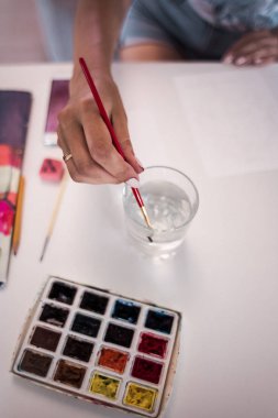 Kadınların elleri kırmızı oje ile suluboya bir defter, üstten görünüm boyalı