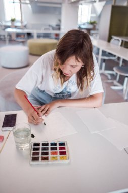  Sanatçı stüdyoda bir resim çizin. Resimde watecolor tarafından. İş günü. İş yerinde bir kadın 