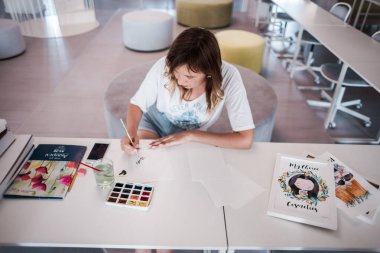  Sanatçı stüdyoda bir resim çizin. Resimde watecolor tarafından. İş günü. İş yerinde bir kadın 