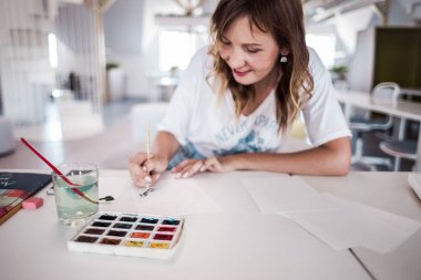  Sanatçı stüdyoda bir resim çizin. Resimde watecolor tarafından. İş günü. İş yerinde bir kadın 