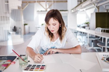  Sanatçı stüdyoda bir resim çizin. Resimde watecolor tarafından. İş günü. İş yerinde bir kadın 