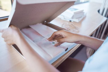 Genç kadın işini kutusunda ambalaj. Hediye fikri. Resimde Victoria Rusyn tarafından. Kırmızı kurdele kutusu