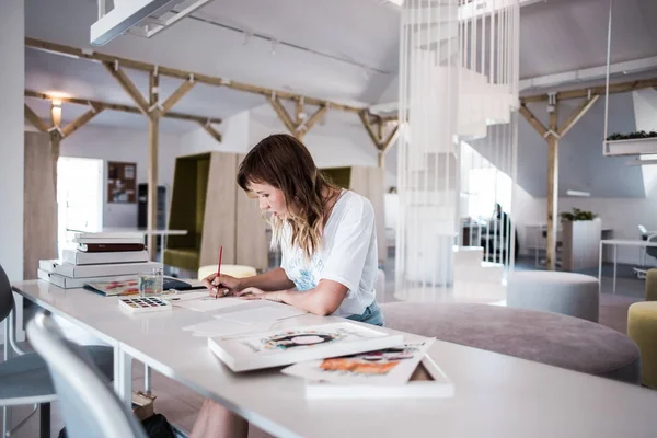  Sanatçı stüdyoda bir resim çizin. Resimde watecolor tarafından. İş günü. İş yerinde bir kadın 