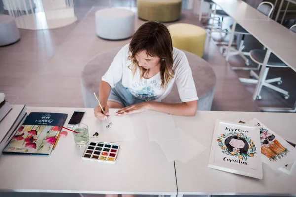  Sanatçı stüdyoda bir resim çizin. Resimde watecolor tarafından. İş günü. İş yerinde bir kadın 