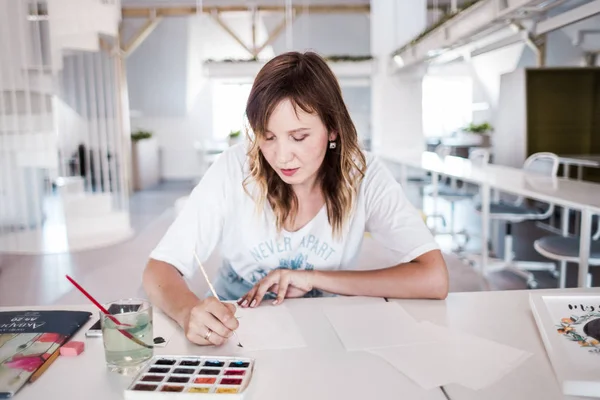  Sanatçı stüdyoda bir resim çizin. Resimde watecolor tarafından. İş günü. İş yerinde bir kadın 