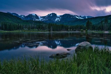 Colorado 'daki Sprague Gölü. Rocky Dağı Ulusal Parkı 'nda gün batımına uzun süre maruz kaldık. Colorado kayaları uzaklardan görülebiliyor. Ateşli bulutlarla dolu renkli gün batımı