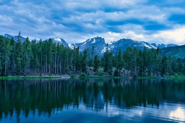 Gün batımında Sprague Gölü. Rocky Dağı Ulusal Parkı Colorado 'da soğuk bir manzara. Kar tepeleri görünür ve göl yüzeyinden yansıyor. Colorado dağlarında güzel ve huzurlu bir manzara