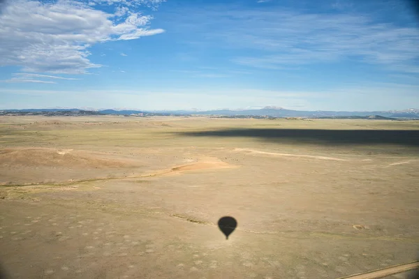 Sombra Balão Quente Olhando Sobre Vasto Plano Com Montanhas Rochosas — Fotografia de Stock